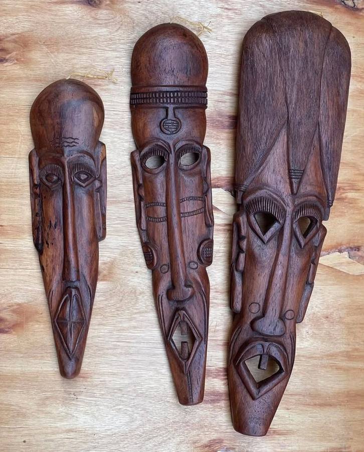 Set of three carved wooden African wall masks with incised patterns and cord hangers