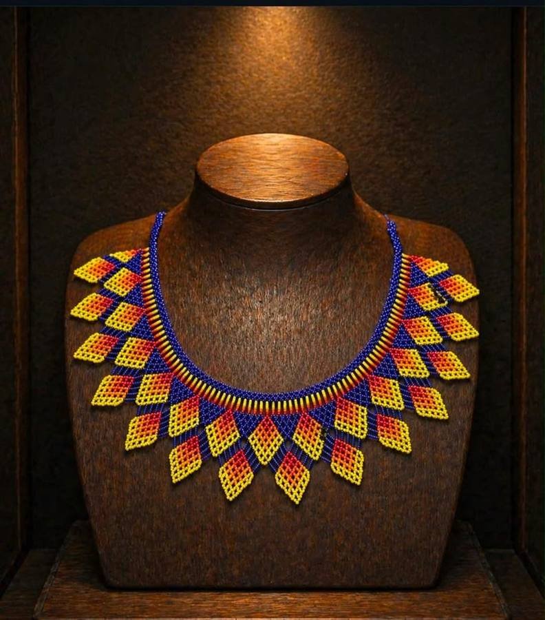 Beaded collar necklace with yellow and red diamond drops on blue, on a display stand