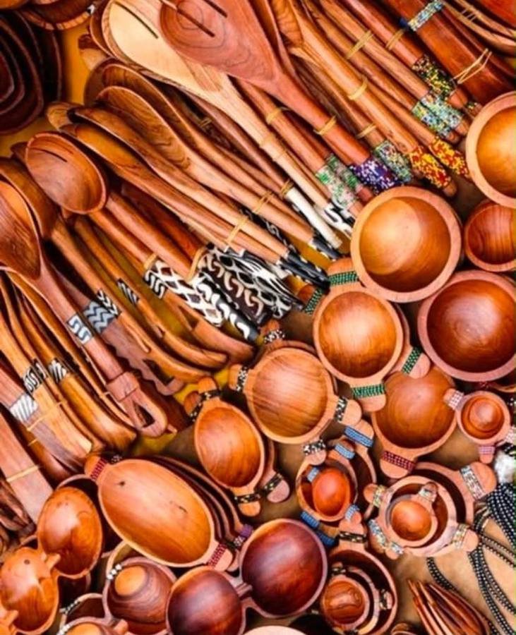 Close view of carved wooden spoons with beaded and patterned handles beside wooden bowls