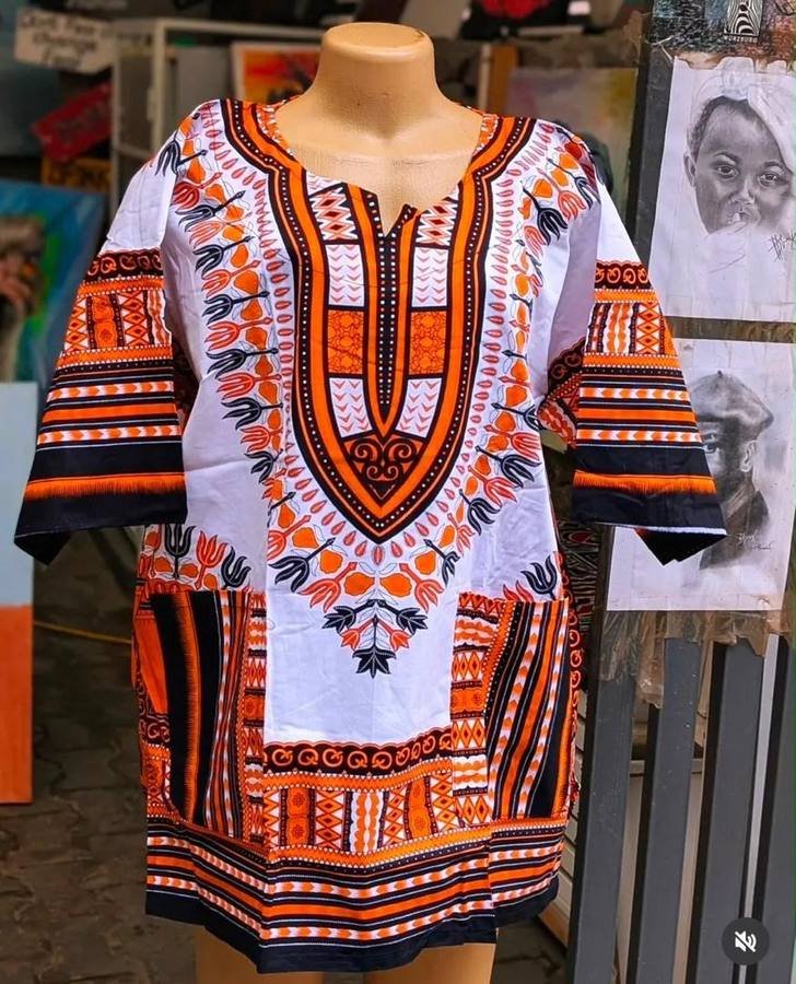 White and orange dashiki top with traditional print on a mannequin