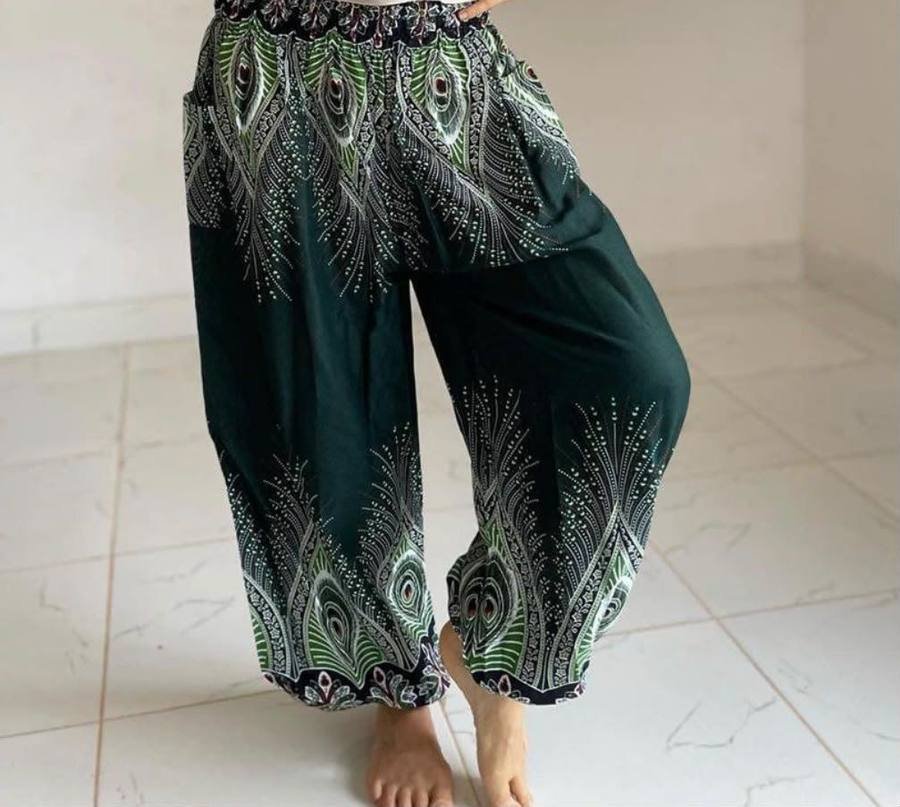 Dark green harem trousers printed with peacock feather patterns, worn