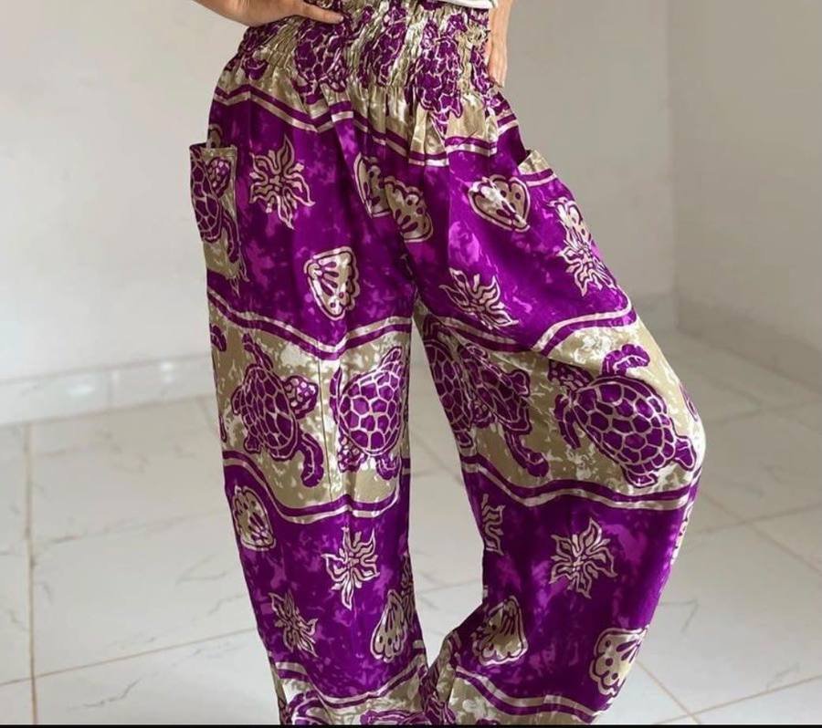 Purple and gold harem trousers printed with turtles and flowers, worn