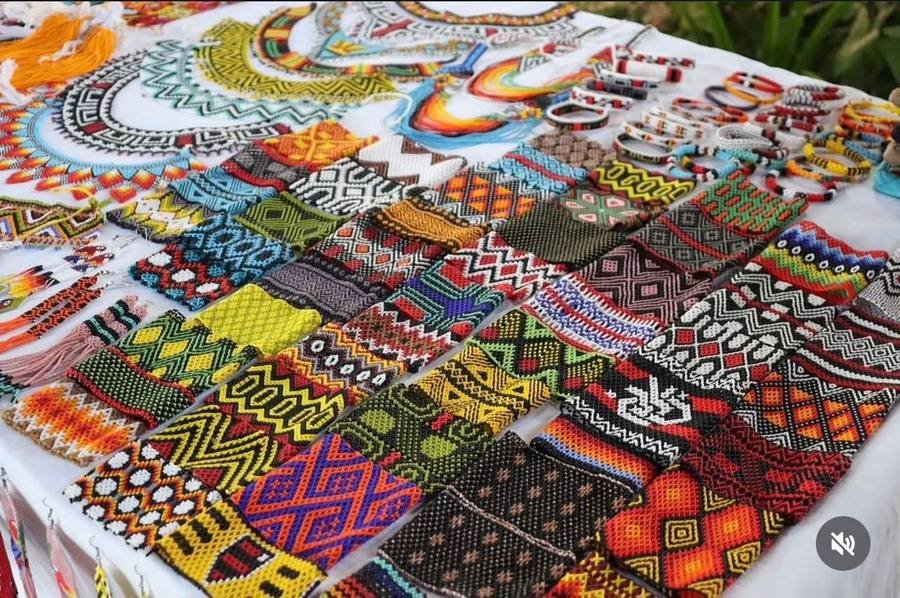 Large table display of handmade Maasai beaded bracelets in many colours and geometric patterns