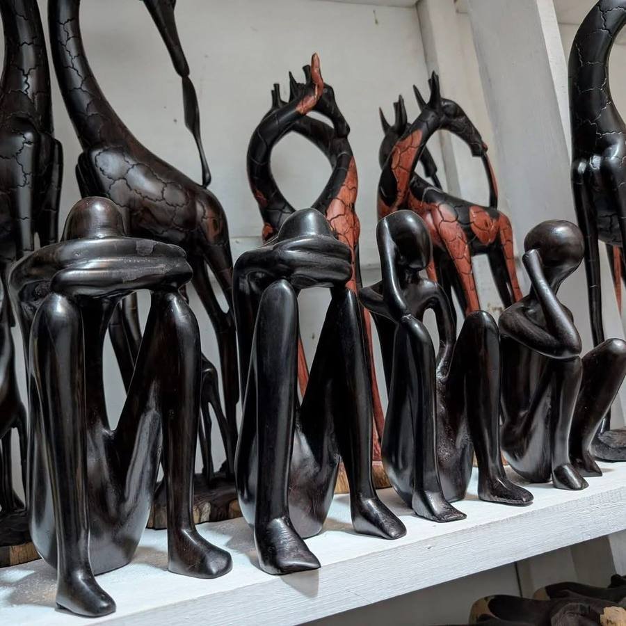 Hand-carved mpingo ebony giraffes and seated thinker figures on a shelf
