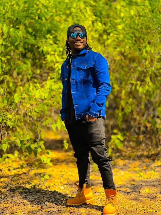 Omary Kitenge Juma, founder of Kitenge Arts, standing outdoors in a blue denim jacket